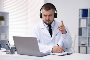 Kulaklıklı doktor içeride bilgisayarla online danışmanlık yapıyor.