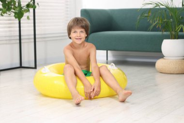 Denizde tatilin hayalini kuruyorum. Evin içinde şişme halkalı küçük çocuk.