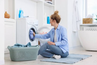 Kirli çamaşırları çamaşır makinesine koyan kadın.