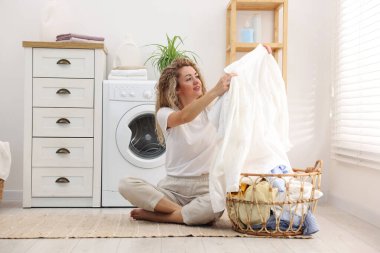 Çamaşır makinesinin yanında çamaşır makinesi olan bir kadın.