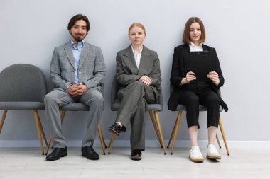 İnsanlar içeride sandalyede kuyrukta bekliyorlar.