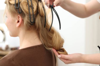 Profesyonel kuaför müşteriyle kuaförde çalışıyor.