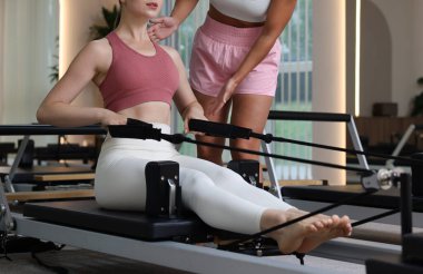 Stüdyoda pilates eğitmeni tarafından denetlenen reformcu kadın, yakın plan.