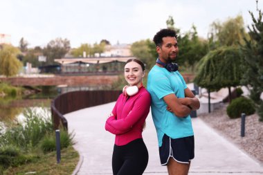 Kulaklıklı gülümseyen koşucular dışarıda çapraz kollarla poz veriyorlar. Metin için boşluk