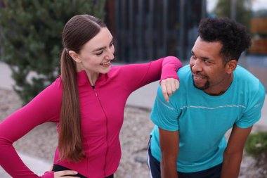 Spor kıyafetlerinde gülümseyen koşucular dışarıda birlikte vakit geçiriyorlar.