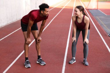 Stadyumda koştuktan sonra dinlenen gülümseyen çift.