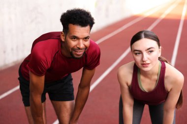 Stadyumda koştuktan sonra dinlenen gülümseyen çift.