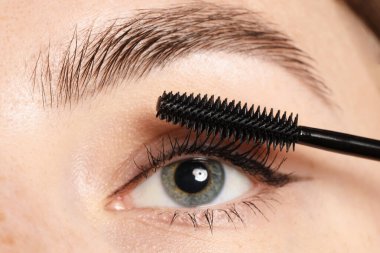Bir kadın kirpiklerine rimel sürüyor, yakın plan.