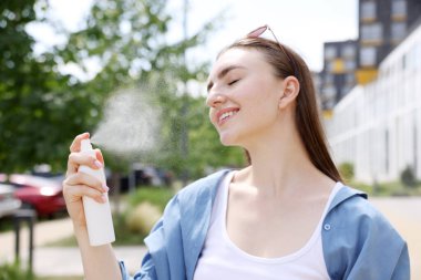 Gülümseyen kadın yüzüne termal su püskürtüyor.