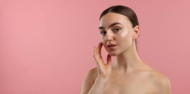 Pembe arka planda krem sürmüş güzel bir kadın.