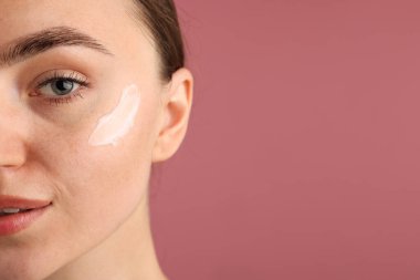 Pembe arka planda krem sürmüş güzel bir kadın, yakın plan. Metin için boşluk