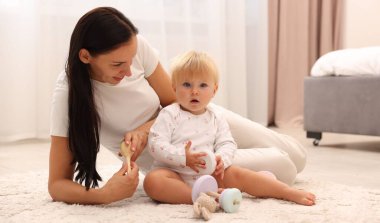 Gülümseyen anne evde sevimli bebeğiyle oynuyor.