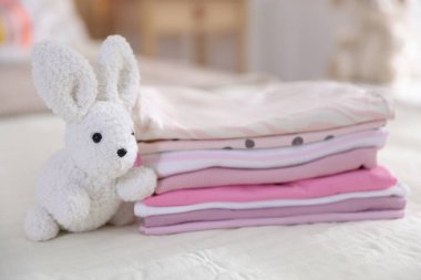 Temiz bebek kıyafetleri ve yatak örtüleri iç mekanda, yakın plan.