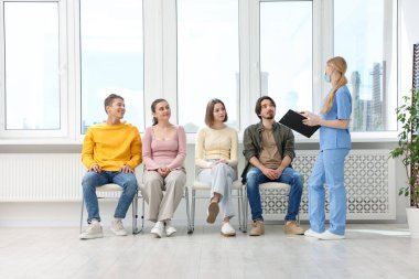 İnsanlar hastanede sandalyelerde kuyrukta bekliyorlar.