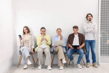 İnsanlar içeride sandalyede kuyrukta bekliyorlar.