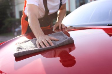 Kaputu gri mikrofiber bez ile silen adam, yakın plan.