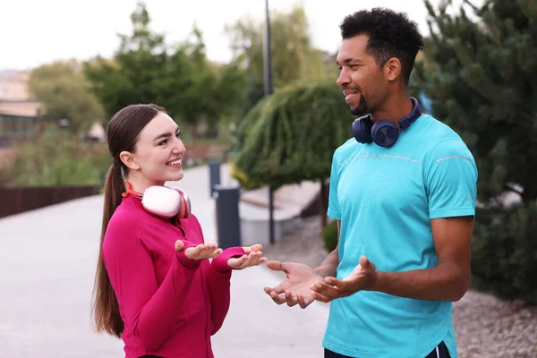 Spor giyim kuşamında, kulaklıklı, dışarıda konuşan koşucular.