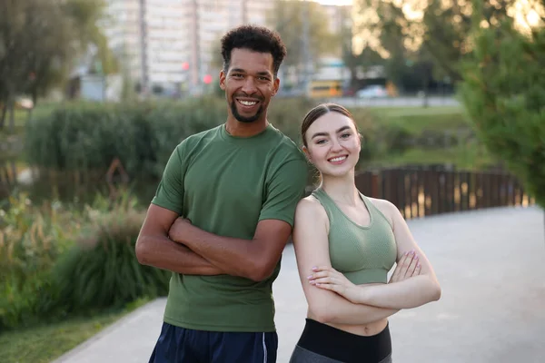 Gülümseyen koşucular dışarıda çapraz kollarla poz veriyorlar.