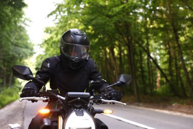 Kasklı genç adam modern motosikleti açık havada kullanıyor. Metin için boşluk