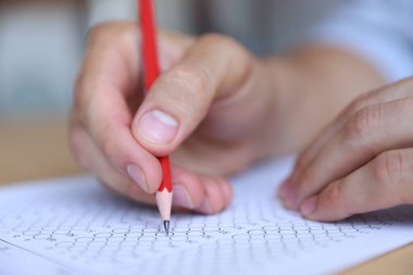 Öğrenci masadaki çoklu seçim testini dolduruyor, yakın çekim. Sınavı geçmek