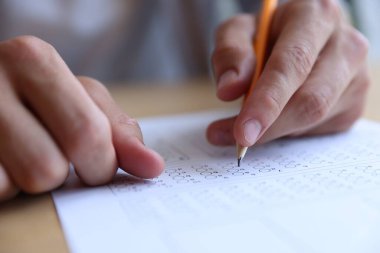 Öğrenci masadaki çoklu seçim testini dolduruyor, yakın çekim. Sınavı geçmek