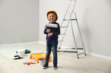 Meslek seçimi. Evin içinde boyacı gibi davranan boya silindirli küçük çocuk.