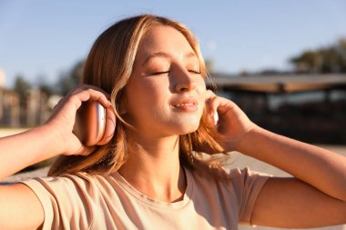 Güneşli bir günde kulaklıklı genç bir kız.