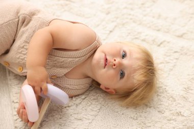 Sevimli bebek evde yerde oyuncakla yatıyor.