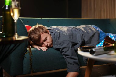 Adam partiden sonra dağınık bir odada kanepede akşamdan kalma.