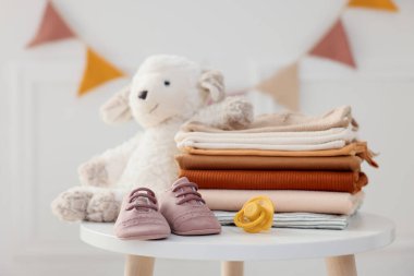 Temiz bebek kıyafetleri ve aksesuarlar beyaz masa içinde, yakın plan.