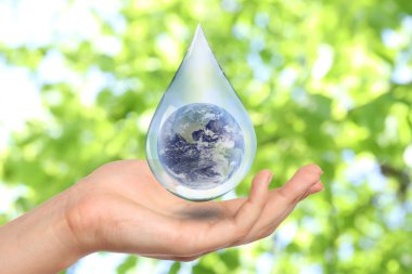 Su kavramını sakla. Bulanık yeşil arka planda Dünya kadının eline düşerken