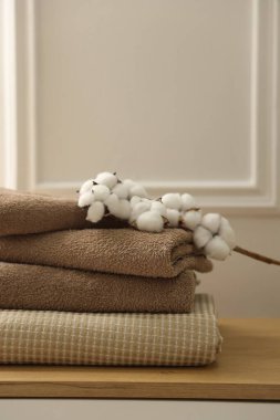 Temiz havlular ve pamuk çiçekleri beyaz duvarın yanındaki ahşap çekmecelerde, yakın plan.