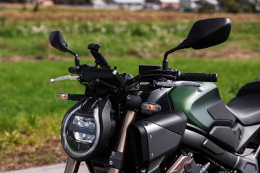 Bir tane modern siyah motosiklet açık hava yolunda park edilmiş.