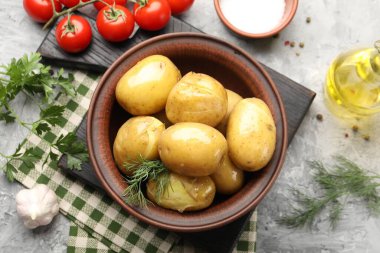 Lezzetli, dereotlu haşlanmış patates, kasede yağ, gri desenli masada tuz ve ürünler, düz uzanma.