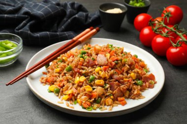 Gri masada servis edilen sebzeli ve jambonlu leziz pilav. Yakın plan.