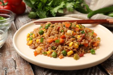 Ahşap masada servis edilen sebzeli ve jambonlu leziz pilav.