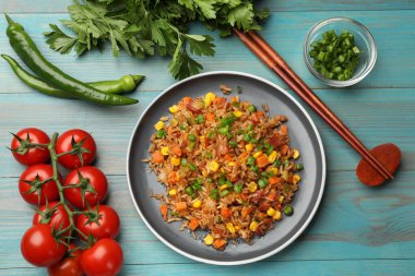 Açık mavi ahşap masada servis edilen sebzeli pilav ve domuz pastırması.