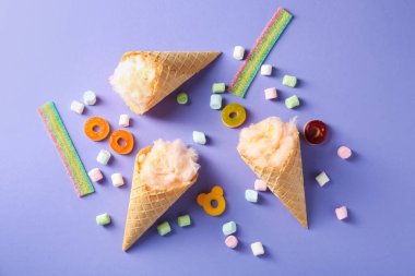 Waffle külahında pamuk şeker ve menekşe arka planda farklı tatlılar, düz uzanma