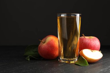 Taze elma şarabı, elma ve yeşil yapraklar siyah masada.
