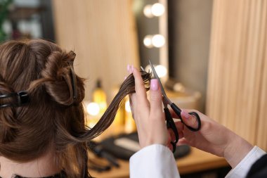 Kuaför kuaförde müşterinin saçını makasla kesiyor.