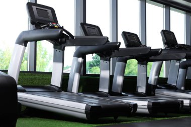 Jimnastik salonunun penceresinin yanında birçok modern koşu bandı var.