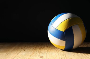 Ahşap zemin üzerinde bir voleybol topu siyah zemin, metin için boşluk