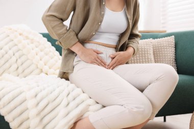 Evdeki kanepede sistit belirtileri gösteren bir kadın var.