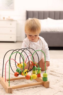 Evde yerde oyuncakla oynayan sevimli bir bebek.