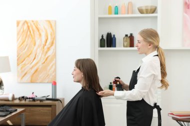 Profesyonel kuaför müşteriyle kuaförde çalışıyor.