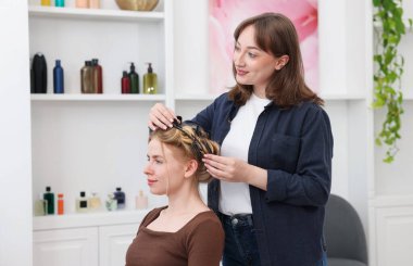 Profesyonel kuaför müşteriyle kuaförde çalışıyor.