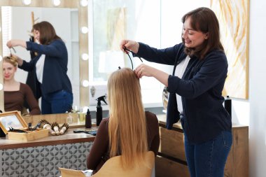 Profesyonel kuaför müşteriyle kuaförde çalışıyor.