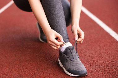 Stadyumda ayakkabısının bağcıklarını bağlayan koşucu, yakın plan.