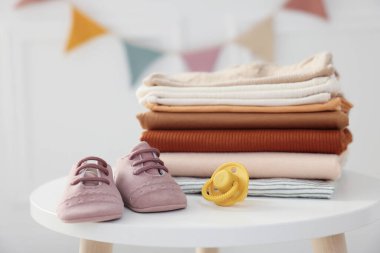 Temiz bebek kıyafetleri ve aksesuarlar beyaz masa içinde, yakın plan.