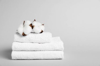 Gri arka planda beyaz havlular ve pamuk çiçekleri, yakın plan. Metin için boşluk